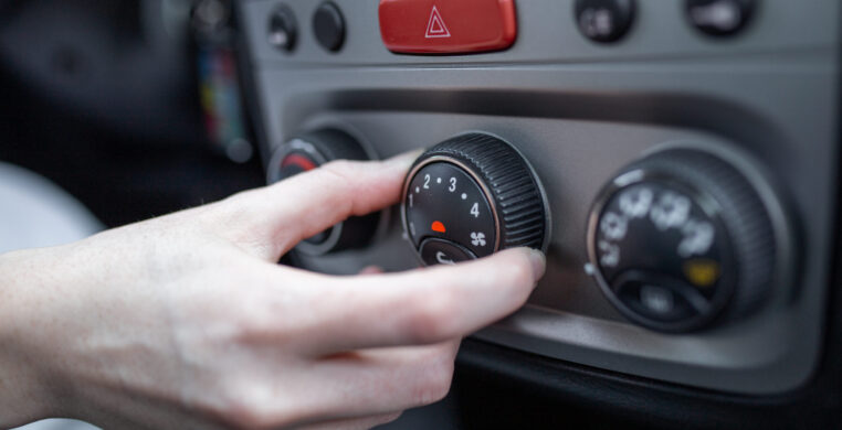 Woman hand turning on car air conditioning system, car air conditioner on off button close up view